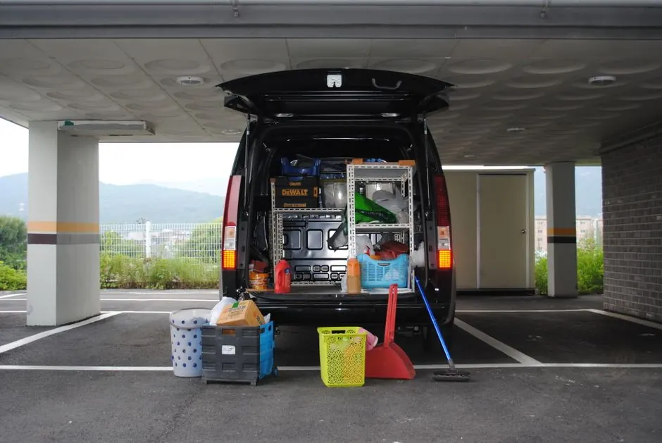 Back view of a black van with equipment in an urban parking area.