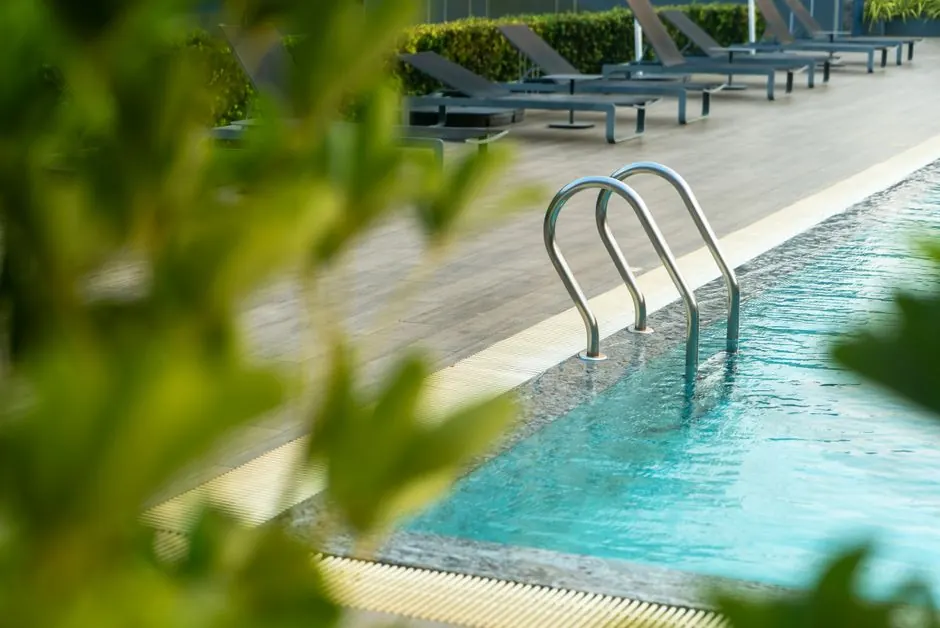 Relaxing outdoor pool area with lounge chairs and greenery, perfect for a summer vacation retreat.